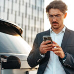 hombre con teléfono inteligente cerca del coche